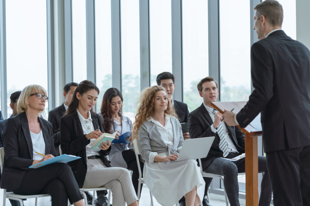 Group of diverse audience listening to business coach at busine